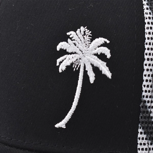 Gros plan sur la broderie palmier blanc d'une casquette de camionneur en maille noire
