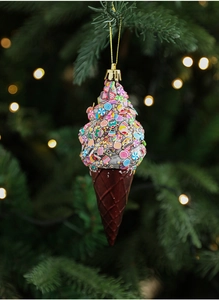 Close-up of ice cream cone ornament with sequins on a lit Christmas tree branch