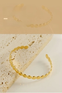 Detailed view of the wave-shaped adjustable golden stainless steel cuff bracelet