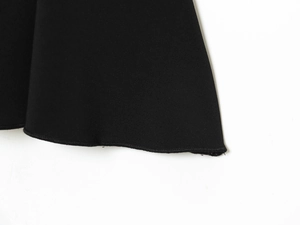 Detailed close-up of the black elastic pleated hem with refined overlock stitching