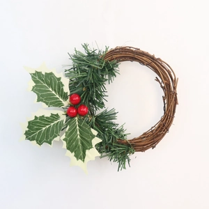 Vue détaillée d'une couronne de Noël en PVC avec baies rouges et aiguilles de pin vert