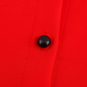 Close-up of vibrant red sleeveless bubble dress featuring smooth black button detailing