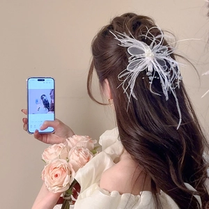 Détail d'une pince à cheveux papillon en plumes et perles blanches sur un mannequin
