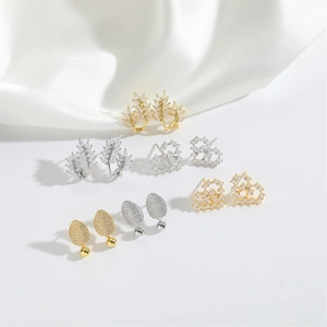 Set of gold and silver leaf earrings with cubic zirconia on white silk background