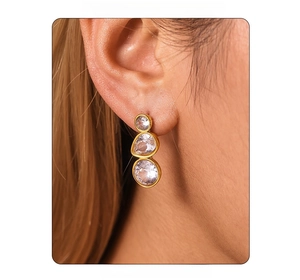 Close-up of three-tier gold drop earrings with inlaid sparkling white zircon stones