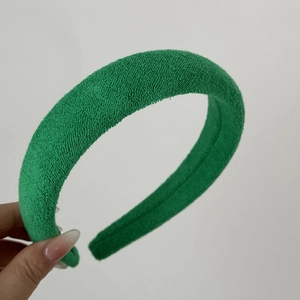 Close-up of green padded sponge headband with soft towel texture held by a hand
