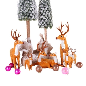 Christmas reindeer figurines with snowy trees and festive ornaments set on white backdrop