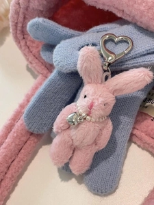 Close-up of pink plush bunny keychain with pearl necklace and silver heart charm