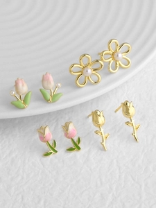 Detail of four pairs of floral earrings featuring enamel tulips and pearl accents on a tray