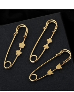 Detailed view of three golden safety pins with decorative floral heart-shaped charms