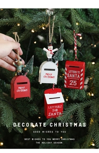 Close-up of red and white metal Santa mailbox ornaments hanging on a Christmas tree