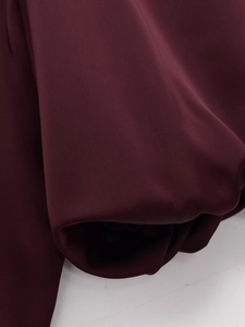 Macro shot of deep burgundy satin fabric texture with soft glossy sheen and smooth folds