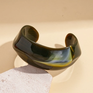 Close-up of marble pattern acrylic cuff bracelet on a textured stone display