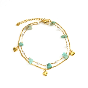 Detail of gold double-layer chain bracelet with turquoise stones and heart charms