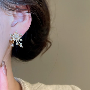 Close-up of snowflake earrings featuring central pearl and sparkling zircon on golden petals