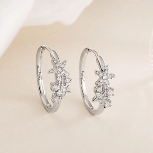 Starfish-shaped silver earrings with cubic zirconia inlay on a soft beige fabric background
