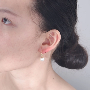 Detail of 925 silver long pearl earrings with gold hooks and sparkling zircon accents