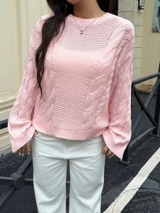 Women's pink cable knit sweater with long sleeves and loose fit in outdoor setting