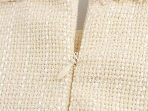Detailed macro shot of the invisible zipper on a beige tweed dress with fine weaving