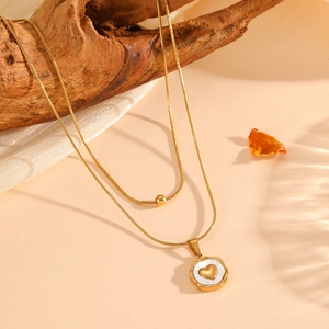 Detail view of 18K gold plated double layer necklace with heart pendant on rustic wood background