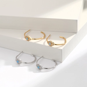 Macro shot of S925 silver devil's eye hoop earrings with blue opal and small crystals