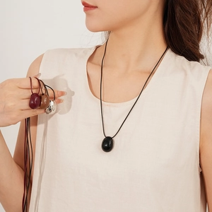 Vue détaillée de pendentifs ovales lisses noir et rouge sur un collier en cordon épuré