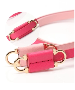 Detail of pink leather belt featuring a golden horseshoe buckle with color splicing design