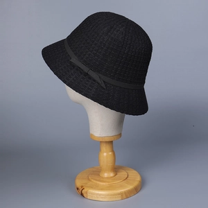 Close-up of black knitted cloche hat featuring textured weave and elegant ribbon bow