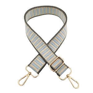 Detail of adjustable blue and beige striped bag strap with gold metal lobster clasps