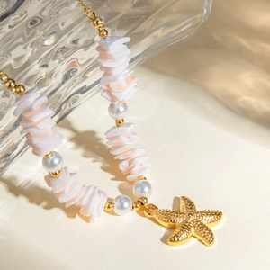 Detailed macro view of 18k gold starfish pendant with mint shell and pearl beads necklace