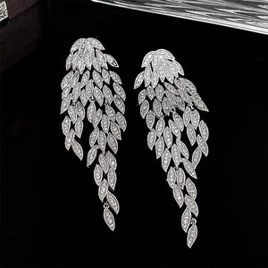 Macro detail of silver leaf tassel earrings with sparkling zircon stones on black background