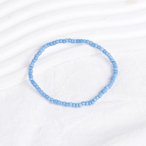 Detailed close-up of blue beaded bohemian bracelet on a white minimalist textured surface