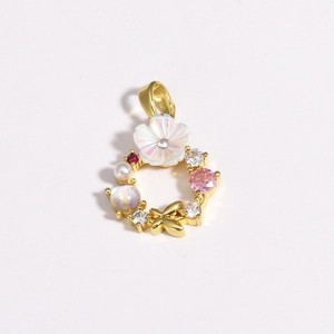 Detail of golden floral pendant with white flower, pink zirconia, and pearls on white background