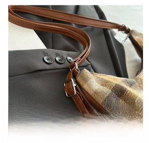 Close-up of adjustable silver metal buckle and retro plaid fabric on shoulder bag