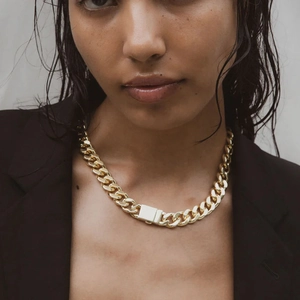 Close-up of a gold chunky Cuban link chain necklace worn with a black blazer