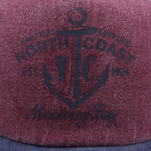 Macro detail of the washed maroon fabric with vintage nautical anchor print and embroidery