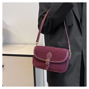 Close-up of burgundy retro suede underarm bag with gold metal buckle and leather trim