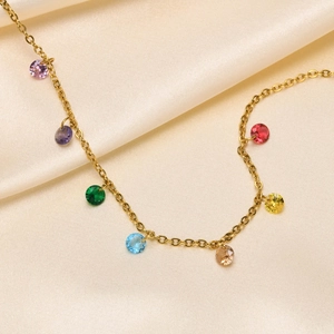 Close-up of gold titanium anklet with colorful zircons on beige silk fabric