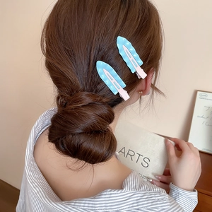 Detail showing wavy blue and pink hair clips worn on a hairstyle with a soft focus
