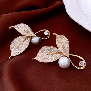 Vista macro di spille a foglia placcate oro 18K con micro cristalli e perle eleganti