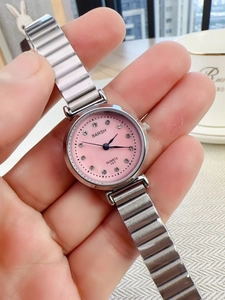 Detailed view of silver steel band watch with pink crystal dial worn on a model wrist