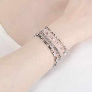 Detailed view of silver stackable bracelet set with white pearls on a model arm