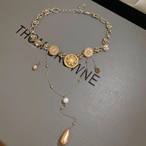 Close-up of vintage gold necklace with sunburst pearl charms and water-drop fringe detail