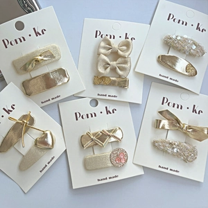 Detail view of 12 piece gold and beige glitter bow hair clips set on display cards