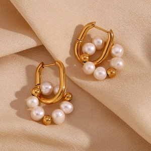 Détail de boucles d'oreilles en U dorées 18K avec perles d'eau douce sur du satin