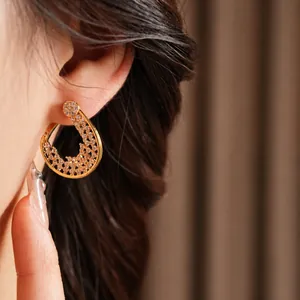 Gold-plated drop hoop earrings with zircon pavé stones on a female model's ear