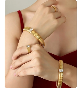 Detail view of gold ripple-textured bangles and rings with rectangular zircon stones