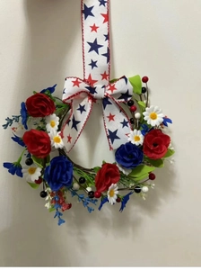 Detail of red and blue roses with white daisies and star ribbon on the festive wreath
