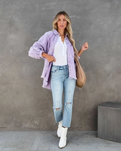 Detail of purple frayed denim jacket paired with ripped jeans and a woven tote bag