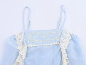Detail of light blue top with white floral lace embroidery and delicate adjustable straps